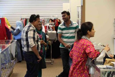 Two Muslim men shopping at an Eid Bazaar with their wives.